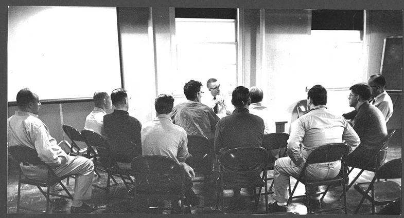 Black and white photograph from the 1950s of about 10 men in a group session at the state hospital.