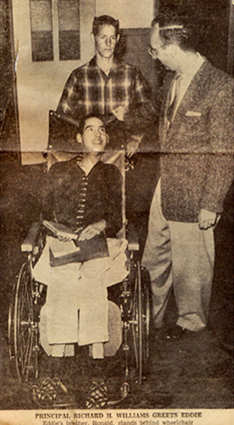 Newspaper photo of Ed Roberts being pushed in a wheelchair by a friend. The principal stands by.